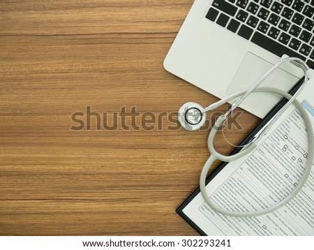 desk\' doctor with computer, stethoscope, medical record application form. top view
