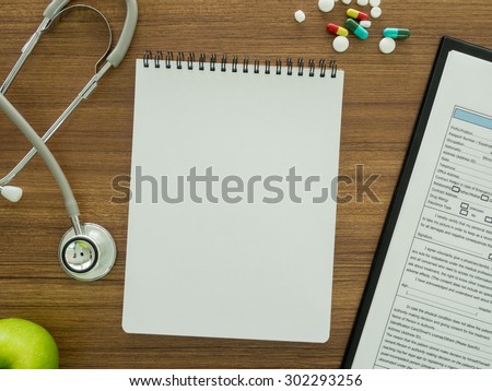 Notebook to record data the patient on a doctor\'s desk.top view.