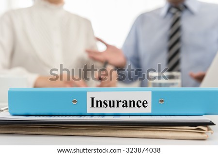 closeup insurance file with two business people meeting in office. Concept of  insurance.