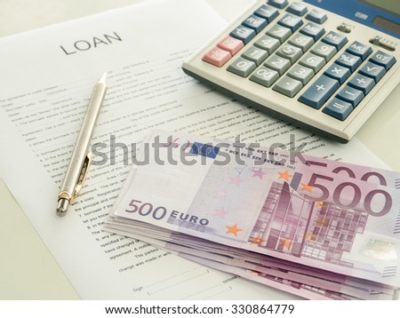 500 euro banknote laying on loan document with pen and calculator on the desk of the bankers.