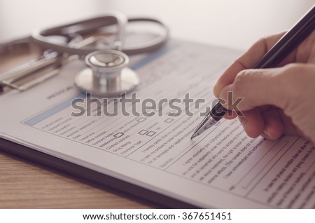 closeup pen in hand\'s doctor notes data on medical document.