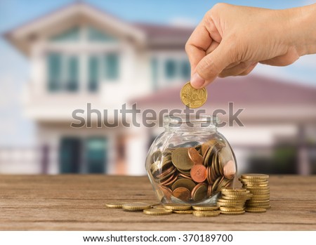 Hand\'s women putting golden coins in money jar. Concept of real estate investments, \
Home insurance, Savings plans for housing.