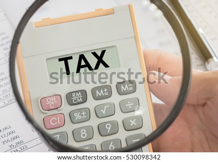 tax word in calculator and magnifier. concepts of taxes, tax planning, taxation.
