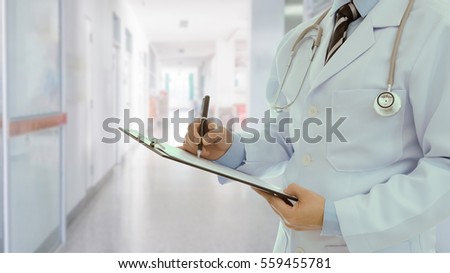 Doctor taking notes on medical document at aisle in ward hospital background.