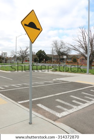 speed bump on asphalt road with yellow and black sign