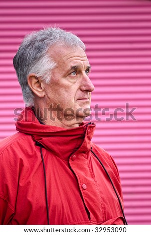 Man in red jacket in front of lurid pink wall