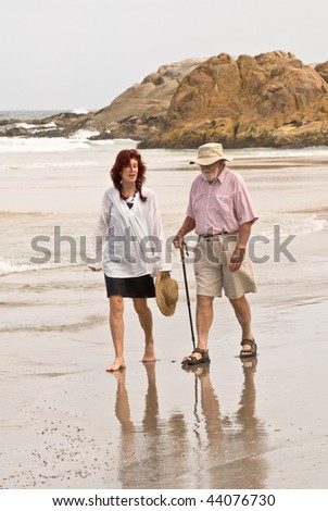 Fifty year old woman and senior man walking on beach