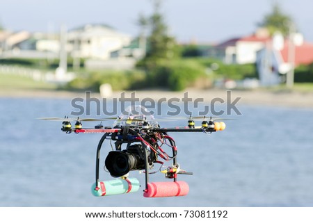 Remote-controlled surveillance helicopter with eight rotors flying over water carrying camera