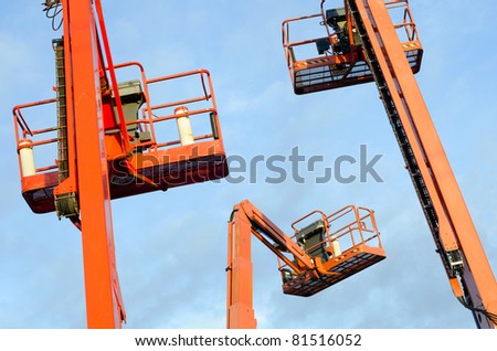 Orange construction crane baskets against blue sky