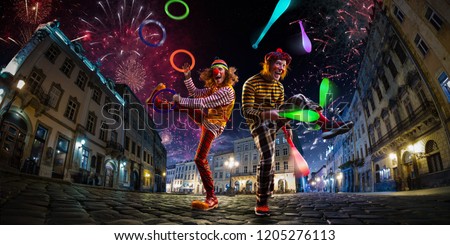 Night street circus performance whit two clowns, juggler. Festival city background. fireworks and Celebration atmosphere.
