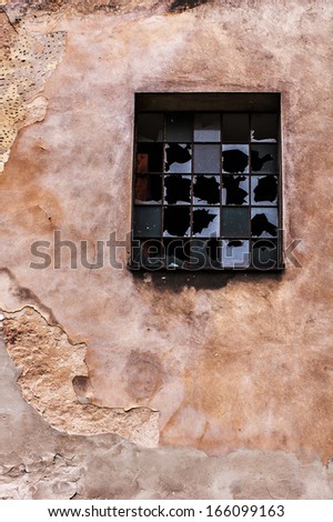 Dilapidated industrial building, chipped and cracked wall, and broken window
