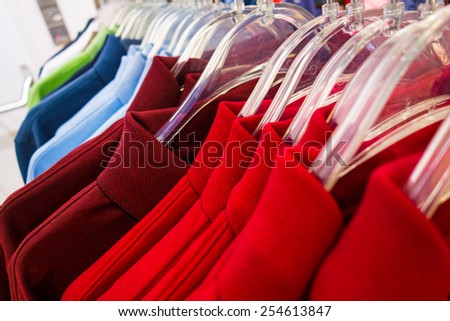 New polo shirts aligned on hangers in fashion store