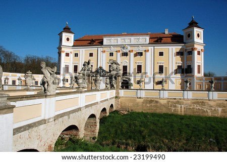 Old castle with a stone bridge decorated with statues in sunny weather.