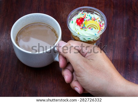 hands hold a cup of coffee on the wood table