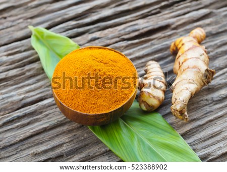 Turmeric powder in wooden bowls on old wooden table. herbal