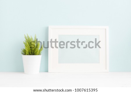White frame mock up and a plant on a book shelf.