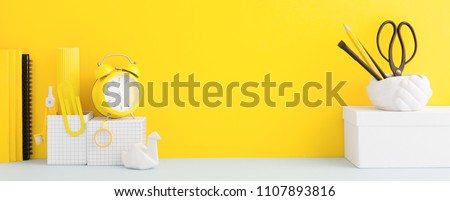 Desk and school supplies over the yellow pastel background. Education, studing and back to school concept Creative desk with yellow wall and stationery.
