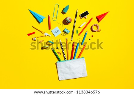 Back to school concept, illustration. Pencil case with various stationery on yellow desk - flat lay.