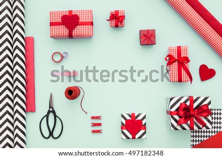 Gift boxes wrapped in red checked paper and the contents of a workspace composed. Different objects on a mint color table. Flat lay.Christmas (xmas) or New year gift packing. Holiday decor concept.