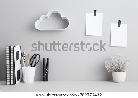 Office desk books, stationery, sticky notes and plant on a gray background.