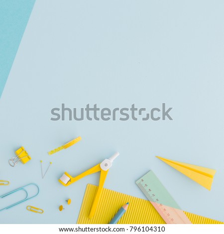 School or office background with stationery, notebook paper, keyboard, crayon, pen, ruller paper clip on blue and yellow colors. Flat lay.