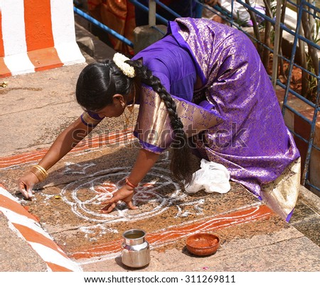 A woman makes a drawing to powders (called kalam) in the floor of the temple Meenakshi in Madurai, in the state of Tamil Nadu, India, during a pilgrimage in August 2005