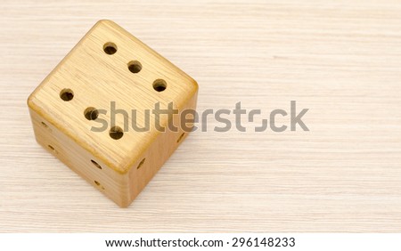 A wooden dice on a wooden table. The number fell to six