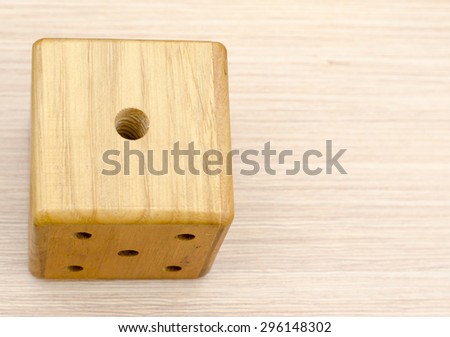 A wooden dice on a wooden table. The number fell to one