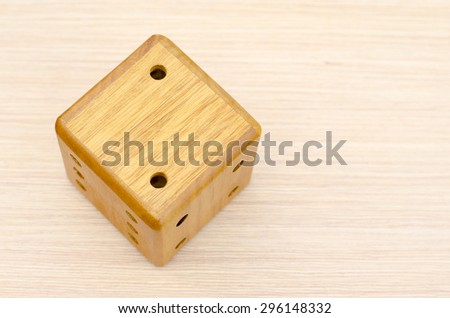 A wooden dice on a wooden table. The number fell to two