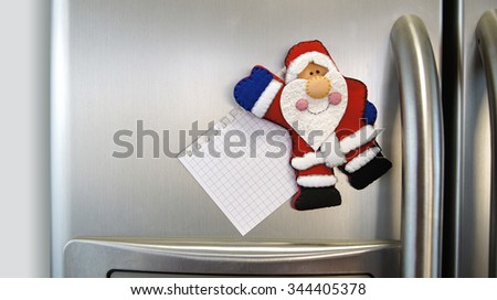 Santa Claus magnet pin with blank note stuck in an aluminum double door refrigerator