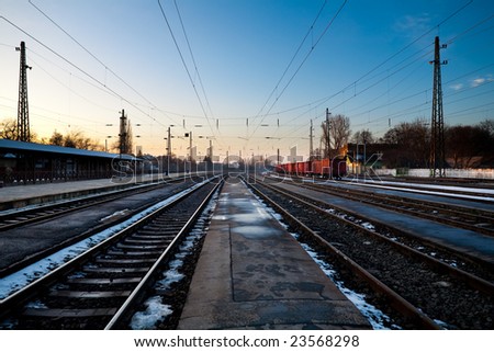 Train station in cold winter at sunset with freight train