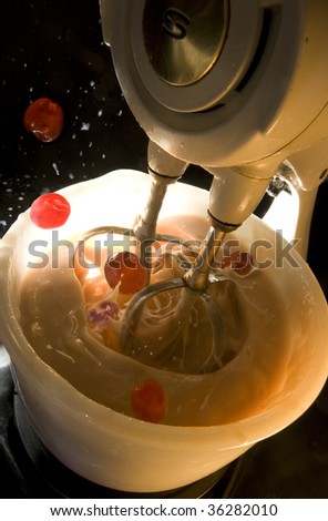 Close up of splashing cake ingredients being mixed in 1950's retro electric food mixer with dramatic lighting.