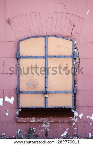 Pink wall with closed yellow window with lock