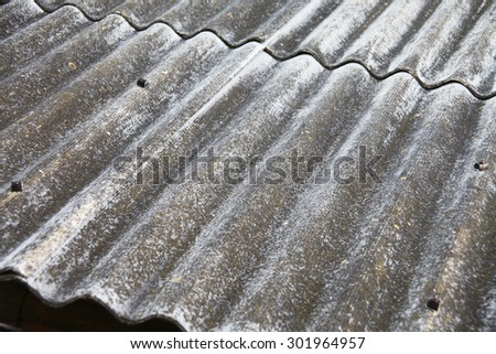 Old slate roof with dirt, lichen and moss at wavy surface.