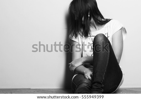 Teenager girl with depression sitting alone on the floor in the dark room
