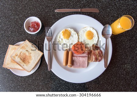 English breakfast with fried eggs, bacon, sausages , ham , tomato and toasts ,Thailand