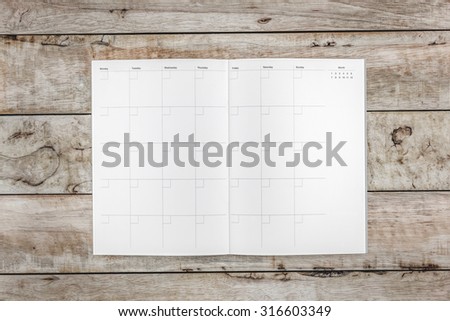 white calendar book on the light brown grunge wood plank background texture from top view / life schedule