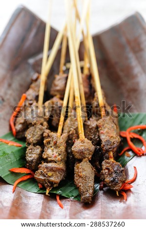 Indonesian beef sate garnished with red chillies.