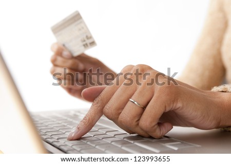 Close up of woman\'s fingers on computer keyboard while holding credit card