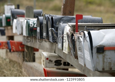 Row of rural mailboxes, one with red flag up indicating mail to be sent.