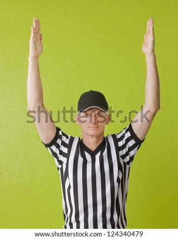 Football referee against green background signaling a touchdown, three quarter length,