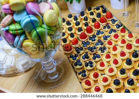 Macaroons, zephyr  and cakes with berries on a dessert table/Cake with berries and cream