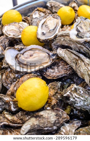 Open oyster shells and lemons on plate in outdoors store/Dish of fresh oysters and lemon.