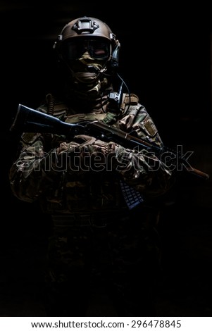 Ranger in camouflage,mask and helmet  standing with arms and looking at the camera on black background