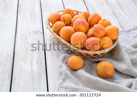 Fresh apricots in a wicker basket on linen napkin on wooden table/A basket of fresh apricots on vintage wooden table
