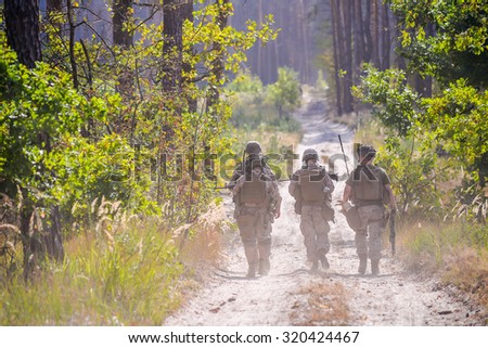 Group of armed soldiers on the road in forest