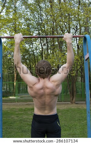 Man is training on the horizontal bar, strong body