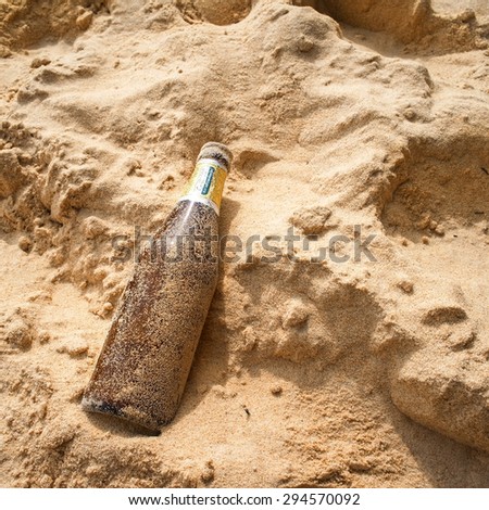 Beer bottle leaving on the sand, Pollution effect from tourism