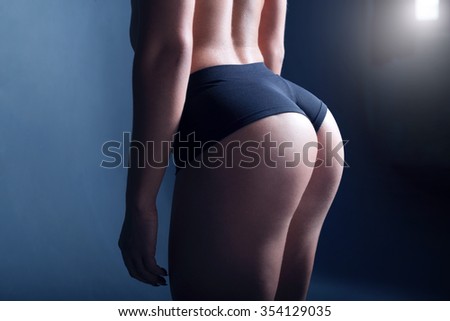 Women fitness motivation. The photo of a sporty girl that was taken in a dark studio with a contrast light.