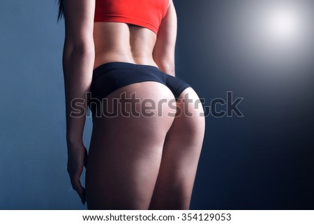 Women fitness motivation. The photo of a sporty girl that was taken in a dark studio with a contrast light.
